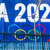 A promotional banner for the LA 2028 Olympics featuring the Olympic rings, displayed on a blue background